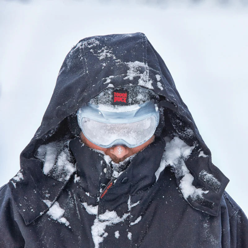 Person wearing a hooded jacket and goggles in a snowy environment