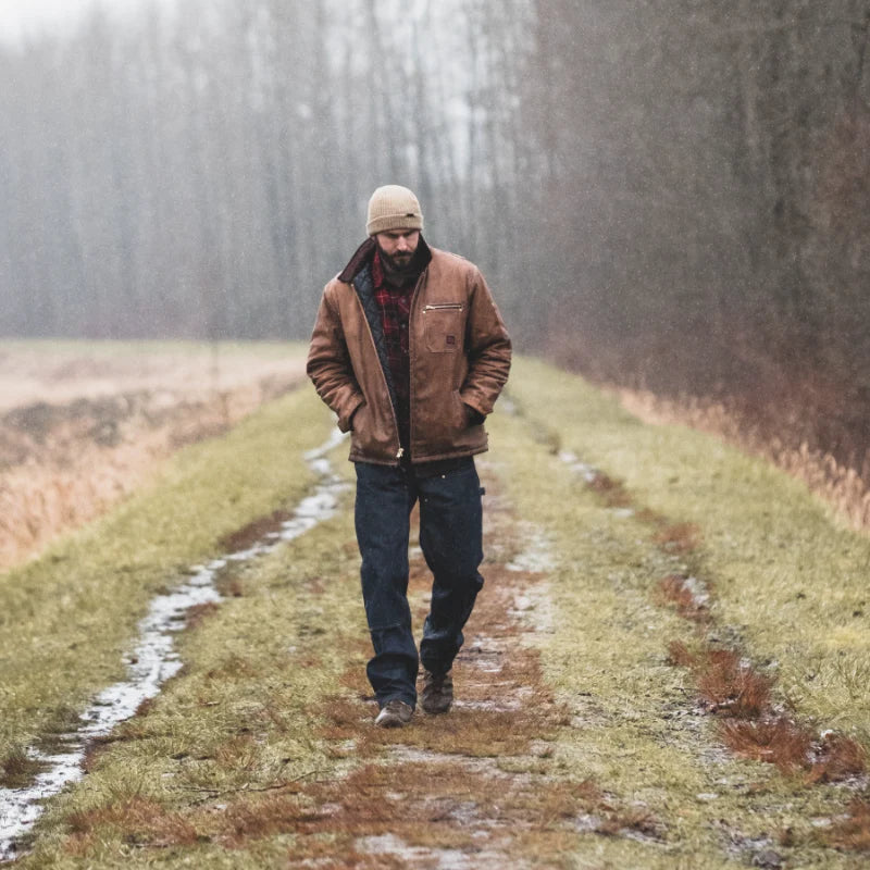 Man walking alone on a foggy path in a forest wearing Brown Jacket and Blue Pants