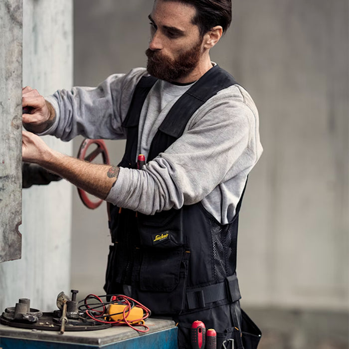 Man working on a piece of machinery with tools around him